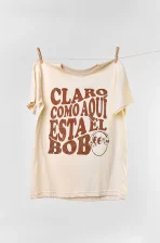Camiseta colombiana “Claro como aquí está el bobo”, inspirada en el humor popular y las canciones de fonda. Ropa de CloClo Marketplace con diseño retro y sello 100 % colombiano.